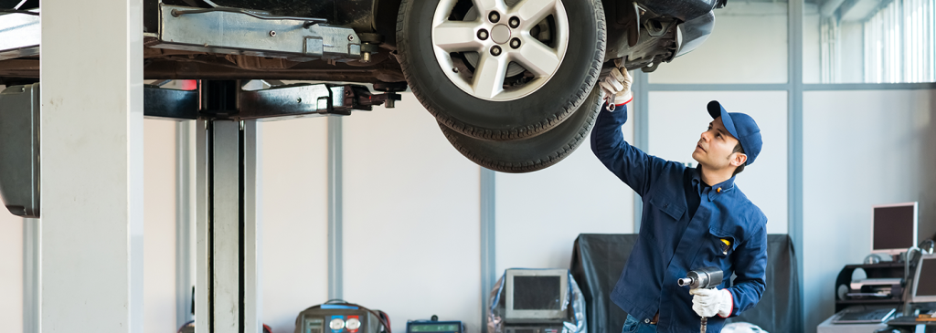 GMC technician inspecting the bottom of a vehicle.