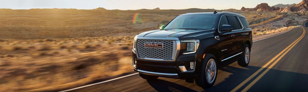 GMC SUV driving on a desert road.